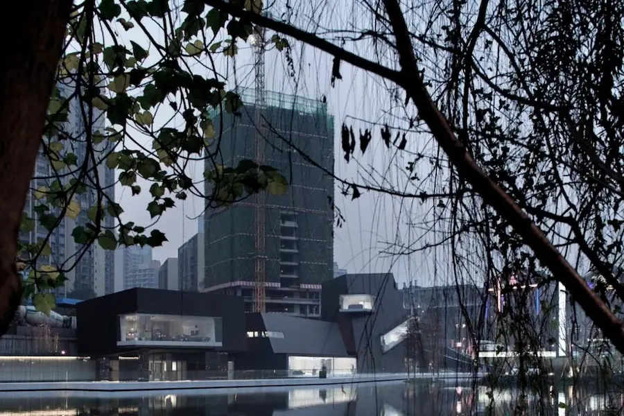 Chongqing Tiandi Art Museum at dusk framed by tree branches
