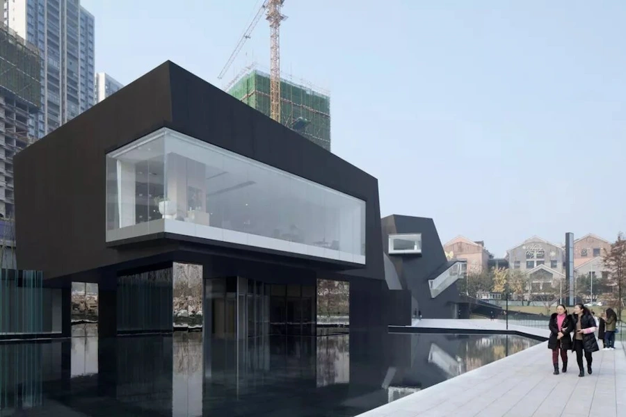 Modern black museum building reflecting in calm water at Chongqing Tiandi