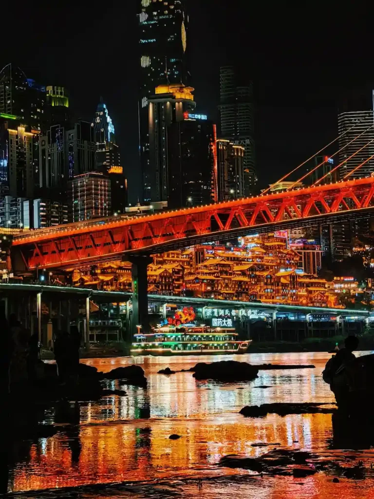 Chongqing beach at night view with illuminated Hongya Cave and bridge lights reflecting on Jialing River water